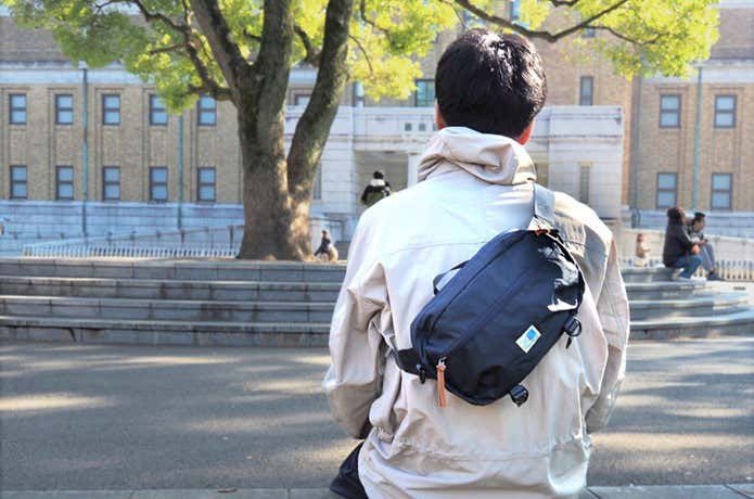 大学の校舎前の広場でカリマーのウエストバッグを背中に背負っている男性
