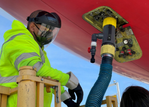 Person collecting wastewater from an airplane during routine servicing by a lavatory truck